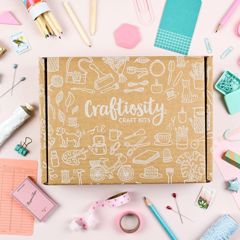 Craftiosity monthly craft kit box surrounded by included supplies like pencils, ribbon, and tools